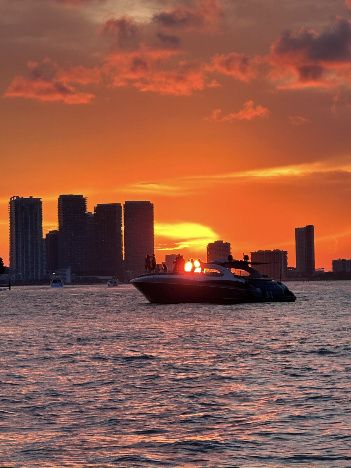 Yacht silhouetted against a vivid orange sunset with the Miami skyline behind it on Biscayne Bay — 1 Life Miami Boat Rental sunset charter