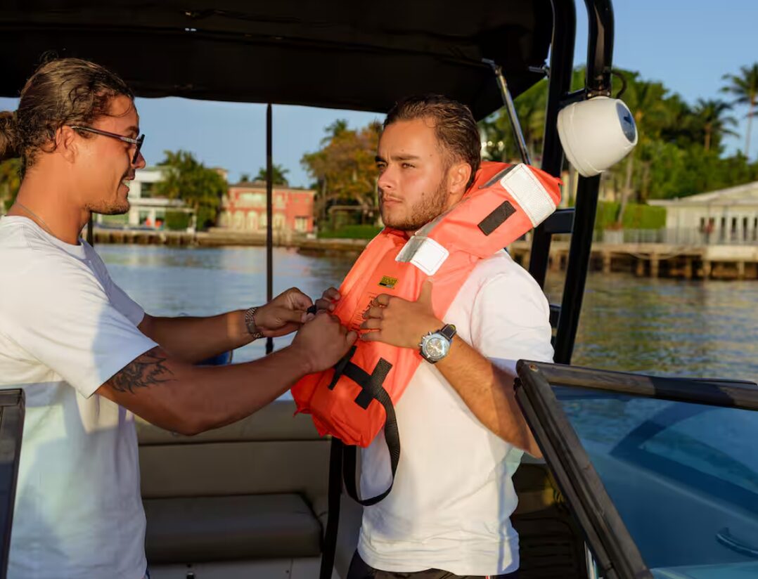1 Life Boat Rental captain fitting a life jacket on a guest before departure in Miami Beach
