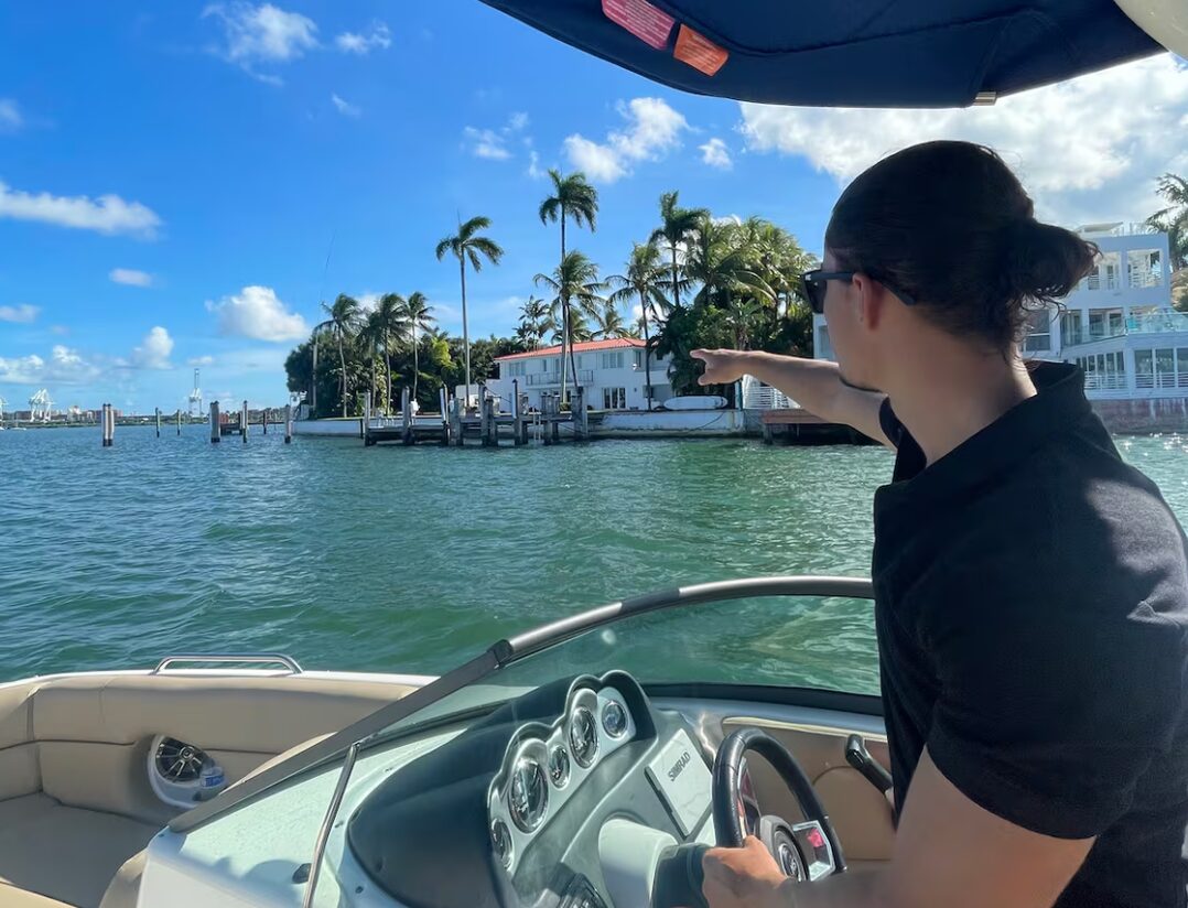1 Life Boat Rental captain pointing out a waterfront mansion on a private Miami Beach boat tour
