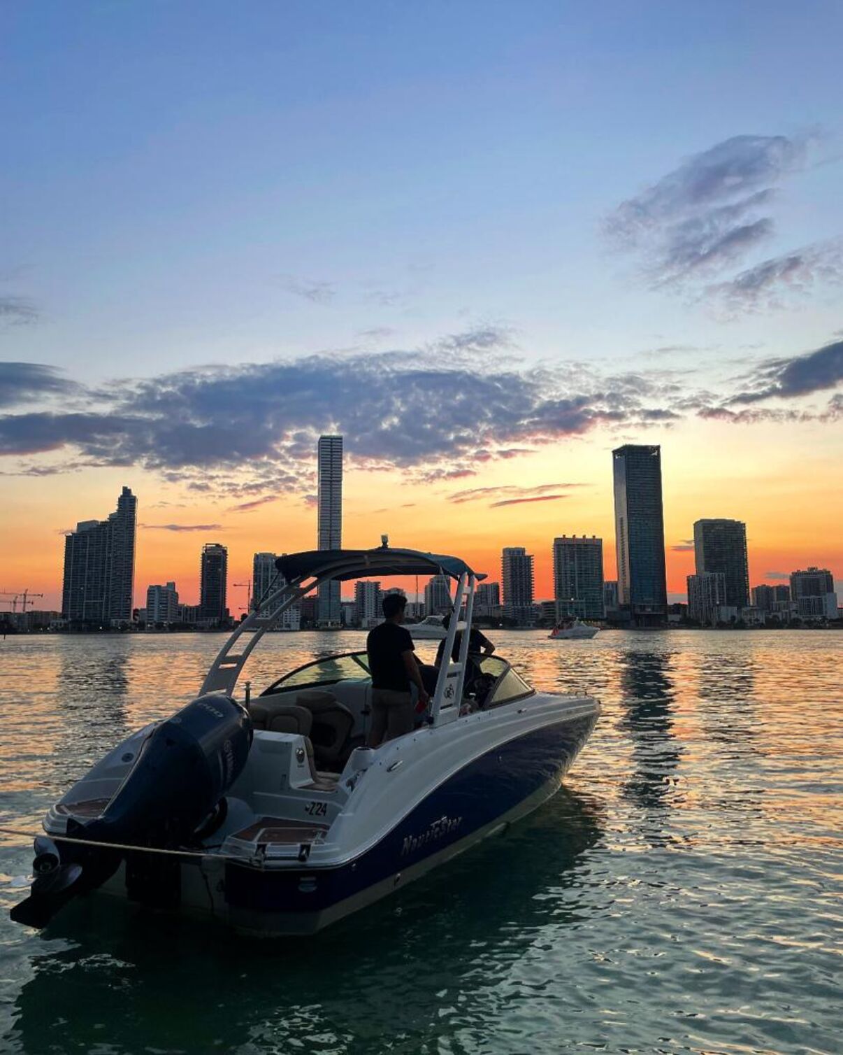Guests aboard a private 1 Life Miami Boat Rental charter anchored on Biscayne Bay with the Miami skyline behind them at dusk — a boat proposal setting in Miami Beach
